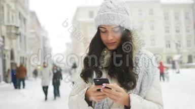 美丽的女人穿着冬衣，微笑着，一边用手机发信息